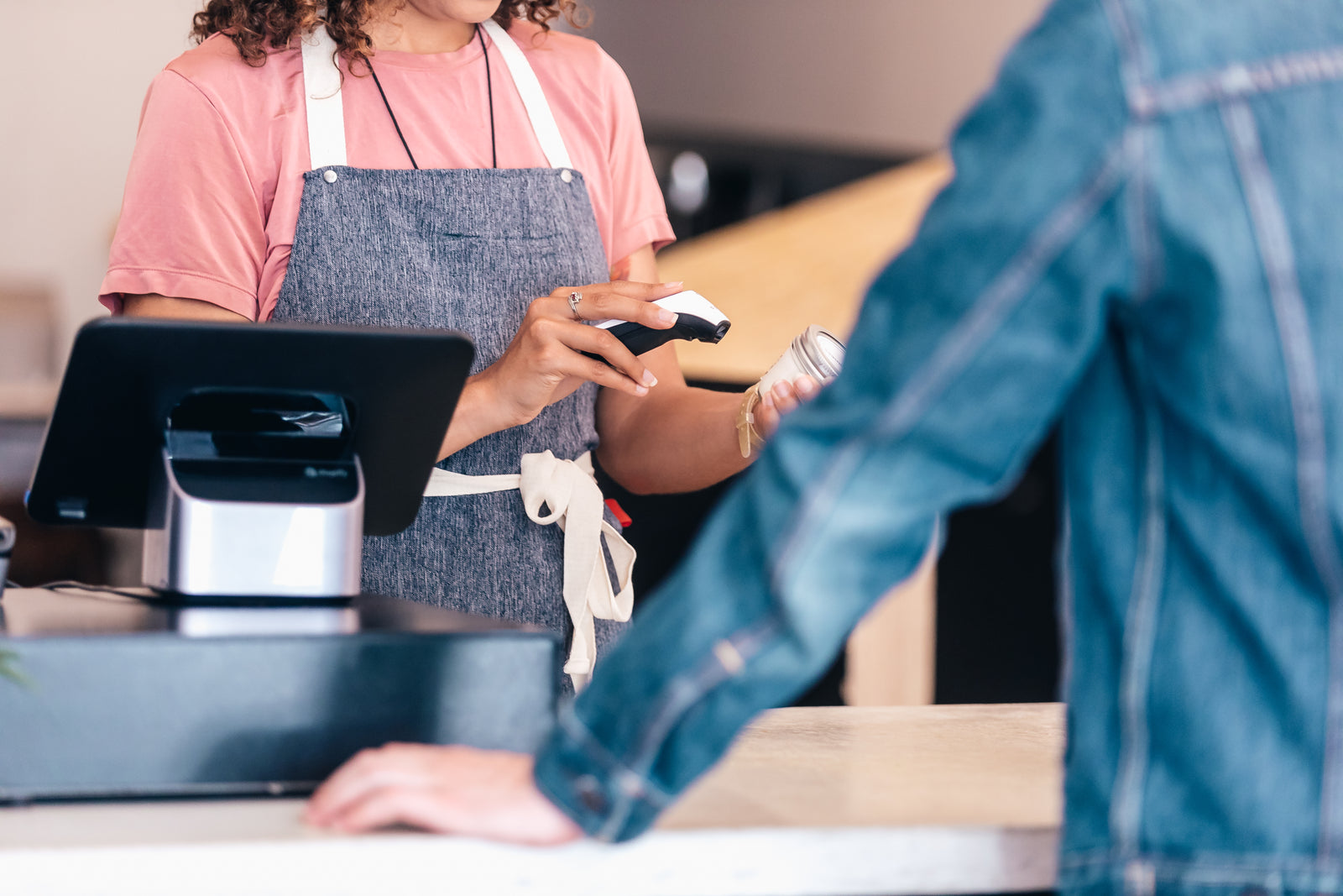 Retail employee using a handheld barcode scanner at a checkout counter