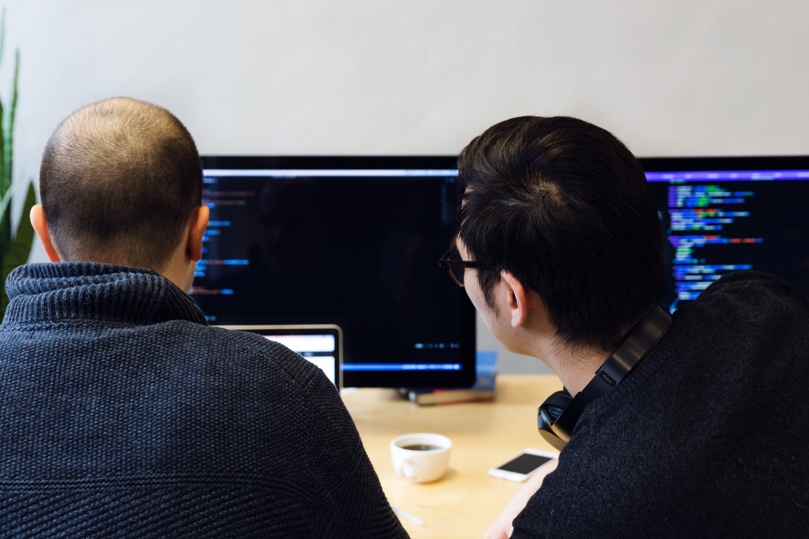 Two software developers reviewing code together at a monitor