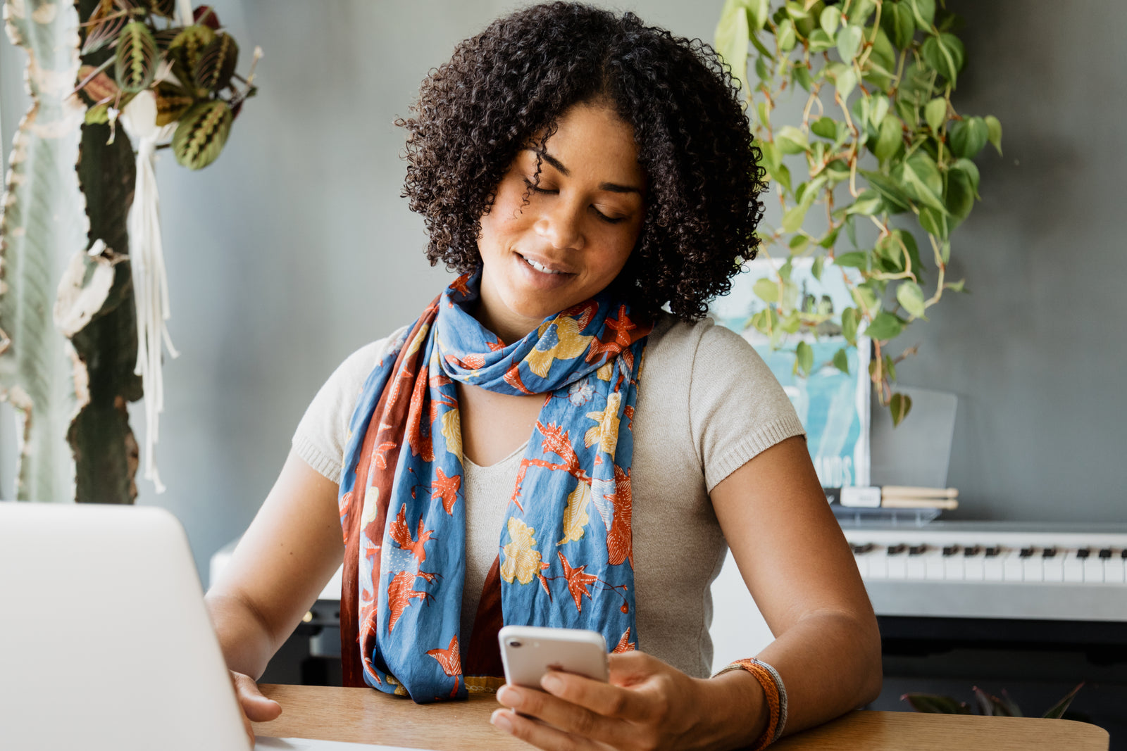 Woman using a smartphone beside her laptop